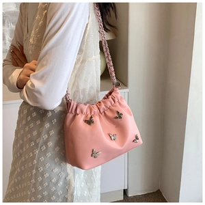 Detail der rosa Beuteltasche mit silbernen Metallschmetterlingen und Leder-Kettengurt