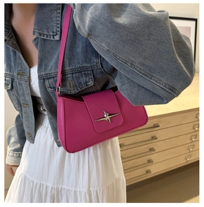 Detail of rose red hobo bag with silver star buckle worn with a denim jacket