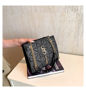 Detail of black geometric embossed chain bag with metal SS logo and fringe tassel