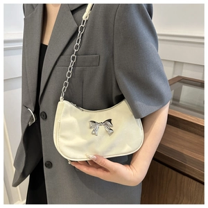 Detail of elegant cream satin hobo bag featuring a 3D silver metal bow and chain strap