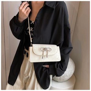 Detail of off-white suede crossbody bag with sparkling silver rhinestone bow decoration