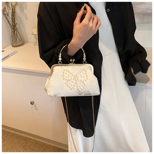 Detail of silk clutch with pearl butterfly embroidery and elegant gold chain strap