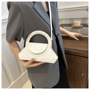 Dettaglio di borsa bianca geometrica con manico rotondo indossata da una modella in blazer