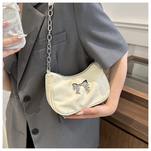 Detail of off-white crescent underarm bag with silver bow accent and metal chain