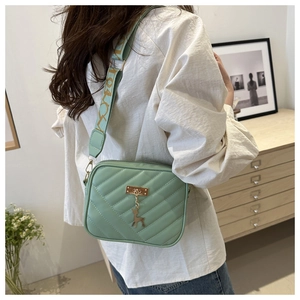 Detail of mint green quilted bag with golden deer charm and patterned wide strap