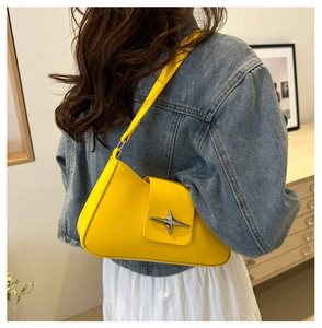Detail of trendy yellow shoulder bag featuring a silver star metallic ornament and sleek finish