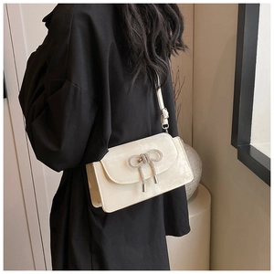 Detailed view of cream leather crossbody bag with sparkling rhinestone bow and fringe