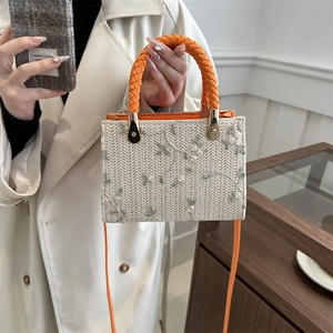 Woven straw handbag with floral embroidery and orange top handle for women