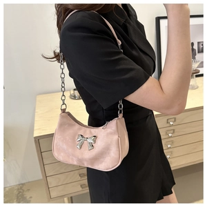 Pink suede underarm bag detail featuring a silver mirror bow and metal chain strap