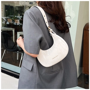 Detail of white crescent shoulder bag with marble texture and golden fashion lettering