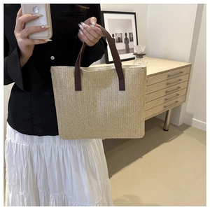 Close-up of the woven straw texture and premium dark brown leather handles on a tote bag