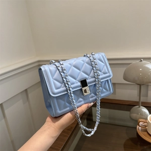 Quilted light blue crossbody bag with silver clasp and chain strap in hand