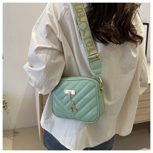 Detail of mint green crossbody bag with V-quilted faux leather and deer charm