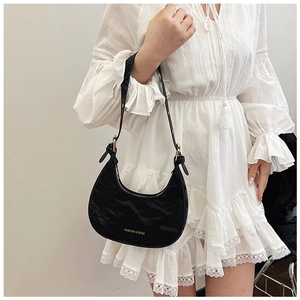 Detail of black crescent bag with pleated texture and adjustable leather shoulder strap