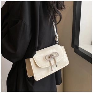 Close-up of cream square shoulder bag featuring a sparkling crystal bow decoration
