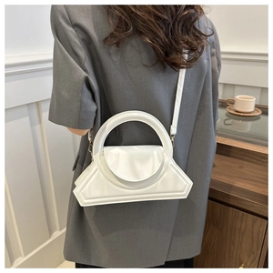 Borsa geometrica bianca con manico circolare indossata da una modella in stile minimalista