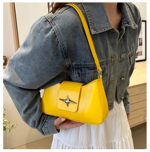 Close-up of bright yellow shoulder bag with silver star buckle on model in denim jacket
