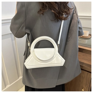 Dettaglio borsa geometrica bianco crema con manico circolare indossata da modella
