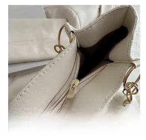 Close-up of golden metal zipper on cream leather tote bag with tweed stitching detail