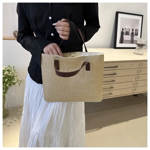Close-up of woven straw tote bag with brown leather handles and magnetic metal closure