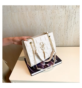 Macro shot of white quilted shoulder bag with gold SS logo and elegant chain strap