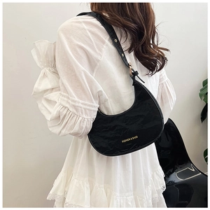 Detail of black crescent shoulder bag with glossy pleated texture and gold hardware