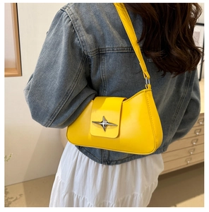 Close-up of vibrant yellow underarm bag with silver star buckle worn by a model