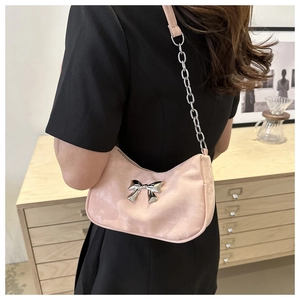 Close-up of pink satin shoulder bag with silver bow detail and metallic chain strap