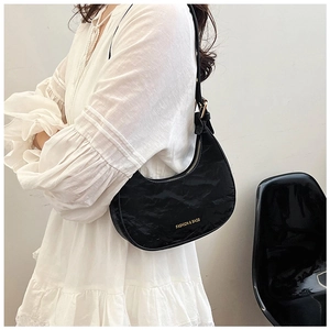 Detail of black crescent shoulder bag featuring pleated texture and gold logo text