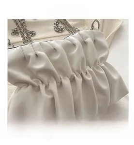 Detail van witte geplooide tas met glinsterende strass handgreep en zilveren metalen ketting