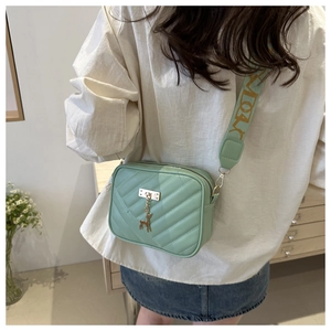 Detail of mint green crossbody bag with V-quilted texture and gold deer charm