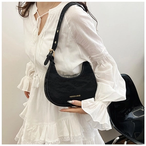 Detail of black crescent shoulder bag featuring pleated texture and golden lettering