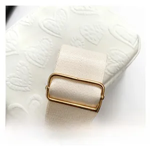 Detail of adjustable wide fabric strap with gold metal buckle on white heart tote bag