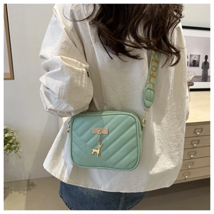 Detail of mint green crossbody bag with diagonal quilting and deer charm decoration