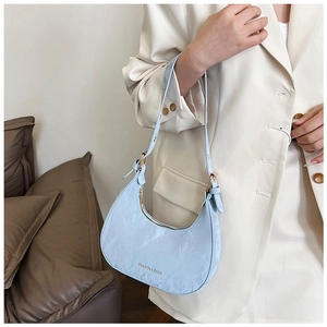 Detail of light blue crescent underarm bag with pleated texture and fashion lettering