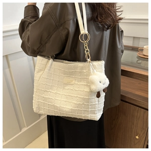 Detail of cream waffle weave tote bag with metal chain strap and cloud charm on model
