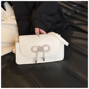Close-up of white suede handbag with sparkling rhinestone bow and crystal droplets