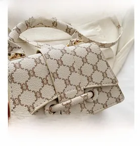 Dettaglio della borsa con monogramma bianco panna, pelle martellata e fibbia