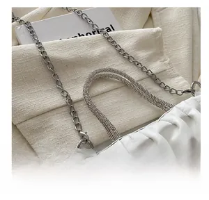 Gedetailleerd beeld van witte geplooide handtas met strass handvaten en zilveren ketting