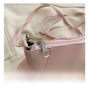 Dettaglio della cerniera argentata e della pelle PU rosa di una borsa a tracolla da donna