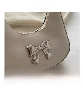 Close-up of a creamy white handbag featuring a stylish 3D silver metal bow ornament