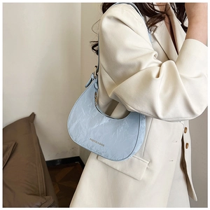 Detail of light blue crescent bag with pleated texture and gold zipper worn by model