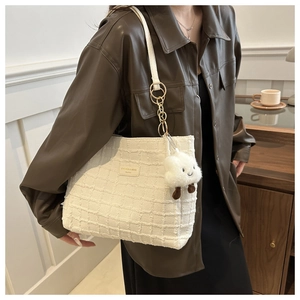 Detail of white woven tote bag with cloud charm and elegant leather brand patch