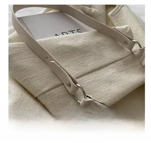 Close-up of textured fabric tote bag with metal ring hardware and leather strap detail