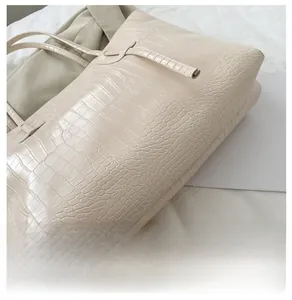 Détail du fond large et de la texture gaufrée crocodile du sac cabas couleur crème