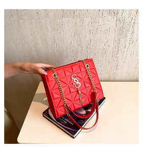 Detail of red geometric embossed shoulder bag with gold SS logo and metal tassel