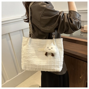 Detail of white tweed tote bag featuring gold chain strap and soft cloud charm accessory