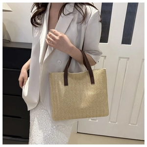 Detail of hand-woven tote bag with beige fishtail texture and brown leather handles
