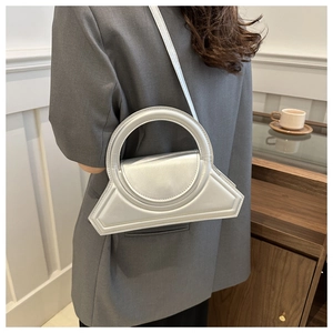 Borsa geometrica argento lucido indossata da una modella in un interno moderno e chic