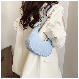 Detail of light blue pleated hobo bag with gold buckle on shoulder strap and soft texture